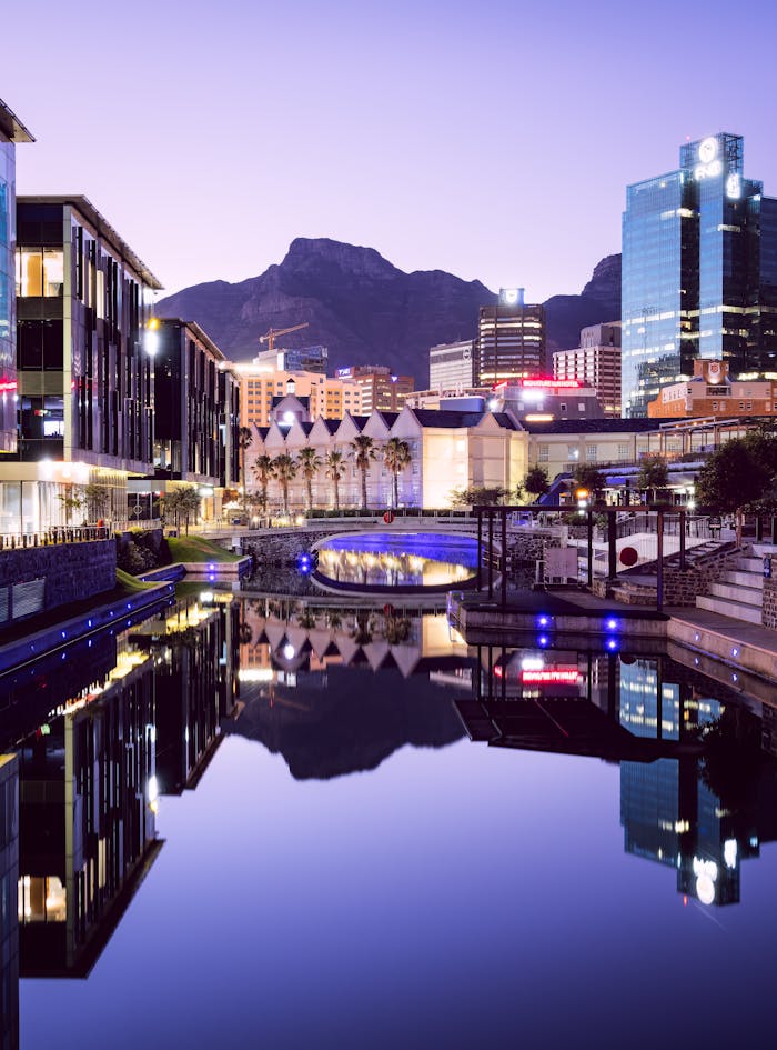 Vibrant modern architecture reflecting on water in Cape Town at twilight.