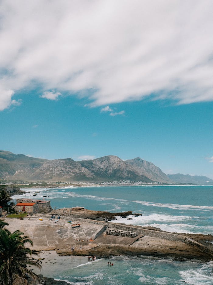 Breathtaking coastal landscape with waves and mountain backdrop in Hermanus, South Africa.