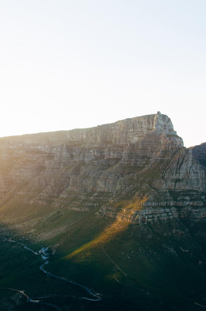 Dramatic sunrise over Table Mountain, Cape Town, showcasing the rocky landscape and bright horizon.