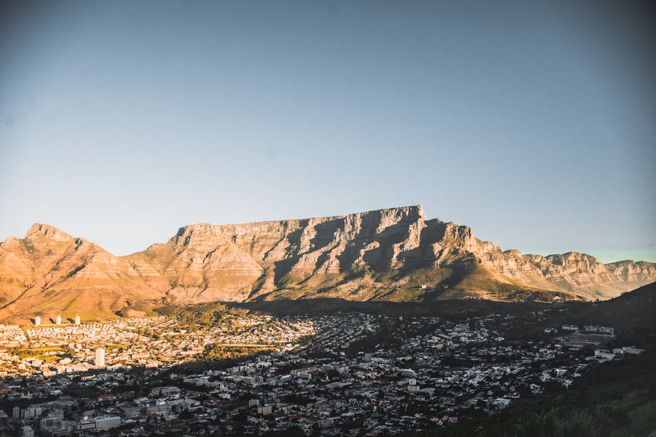 A breathtaking view of Cape Town's cityscape with the iconic Table Mountain in the backdrop during sunset.